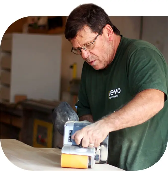 Marceneiro da Revo Marcenaria plainando uma madeira para produção de móveis sob medida em São Paulo.