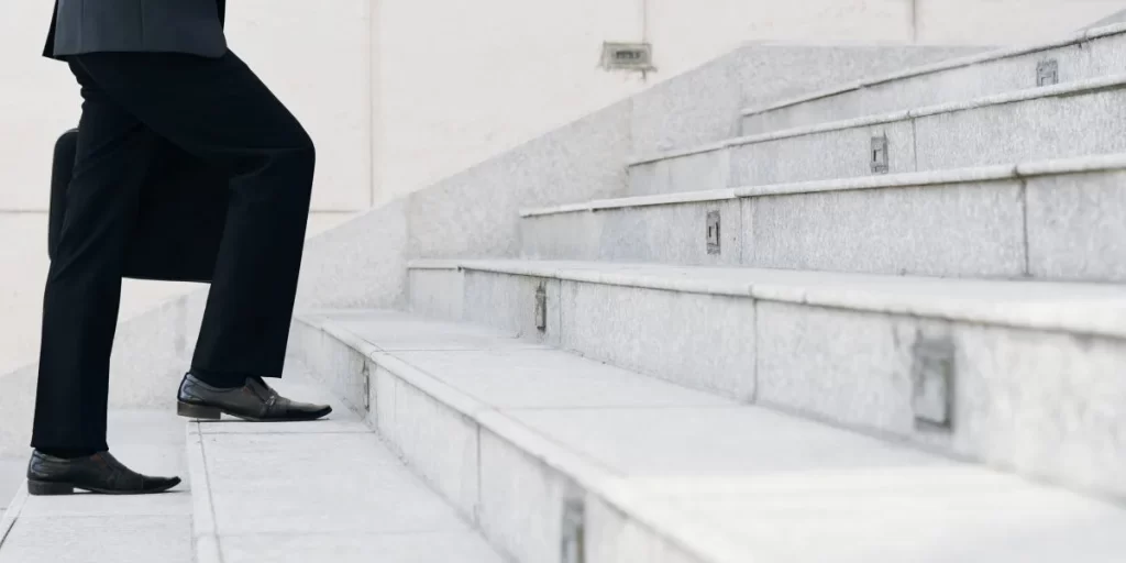 Homem de terno subindo escada de alvenaria, simbolizando a espiritualidade no trabalho e o crescimento profissional com propósito.