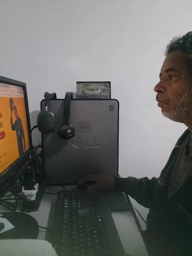 Seu Domingos Eletricista em seu escritório, concentrado trabalhando no computador, desenvolvendo conteúdos e atualizações para seu site profissional.